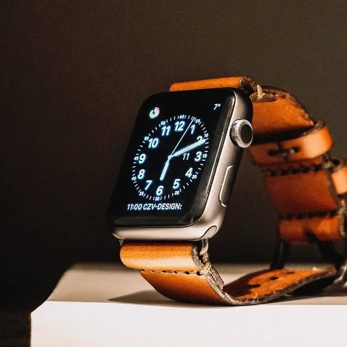An Apple Watch with a tan leather strap