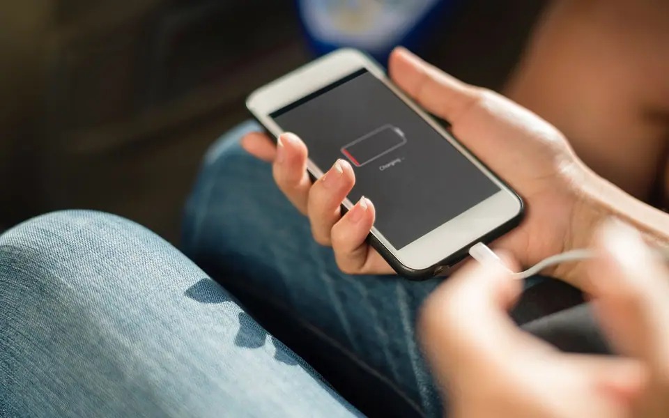 A hand holding a phone showing a low-battery charging screen
